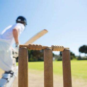 Close Up Of Wooden Stump By Batsman Standing On Field Against Clear Sky